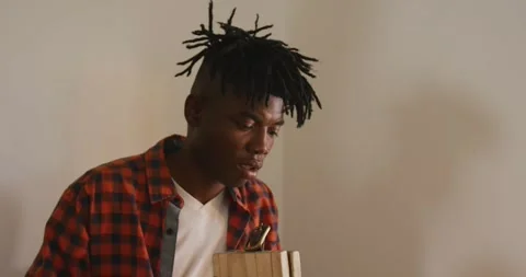 Focused african american craftsman with dreadlocks preparing belt in leather Stock Footage 337223885