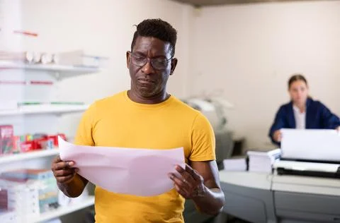 Focused African American man checking the print quality and accepting color Stock Photos