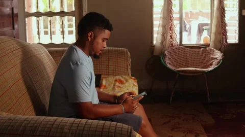 Focused african american man using his smartphone at home Video stock 328176084