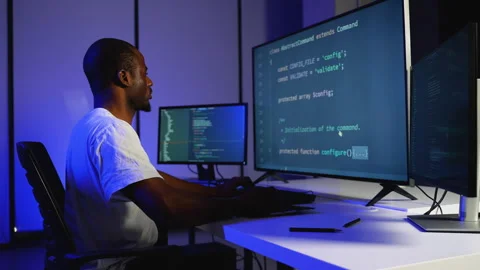 Focused African American programmer coding on multiple monitors Stock Footage 305009433