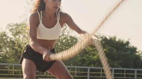 Focused african american woman in tracksuit doing exercise with ropes outdoors Stock Footage