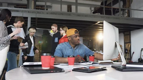 Focused african businessman working on the computer while her cowoker discussing Stock Footage 108409892
