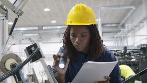 Focused African engineer inspecting machine with flashlight Stock Footage 147500894