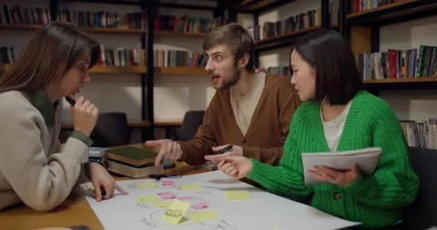 Focused and active guy student together with his female colleagues sitting at Stock Footage 313357488