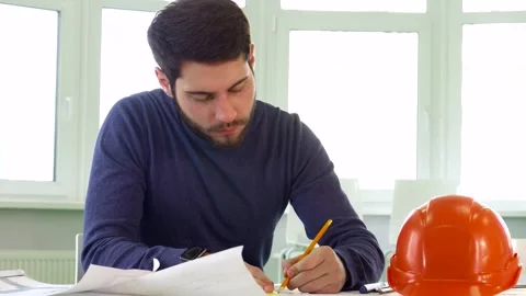 Focused architect meticulously drawing lines on a detailed plan Stock Footage 311952707