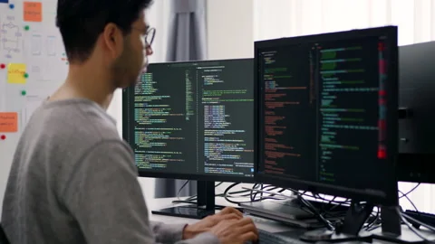 Focused Asian Male Programmer Coding on Multiple Monitors in Modern Office. Stock Footage 300246209