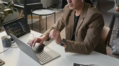 Focused Asian Male Software Developer Coding on Laptop in Office Stock Footage 336750235