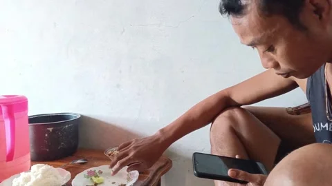 Focused Asian Man Looking at Smartphone Screen After Finishing His Meal Video stock 335019816