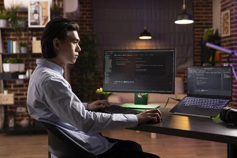 Focused asian man using multiple devices to debug software Foto stock