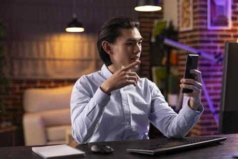 Focused asian man using smartphone for video call with colleagues Foto stock