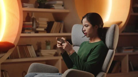 Focused Asian woman plays mobile games in home study, enjoying gaming hobby Stock Footage 343664553