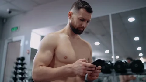 The focused athlete writes down on the phone the number of exercises performed Stock Footage 156854595