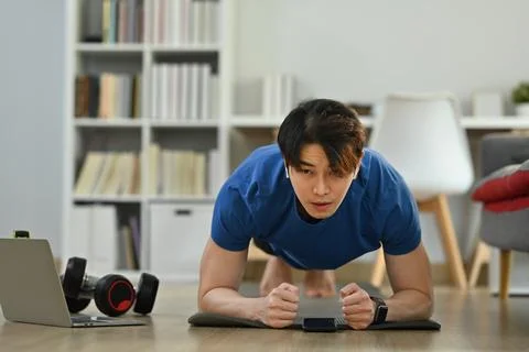 Focused athletic man doing plank exercise during morning workout at home. Sport Stock Photos