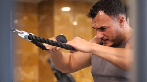 Focused athletic man training upper body with cable crossover rope extensio.. Vidéo 344032170
