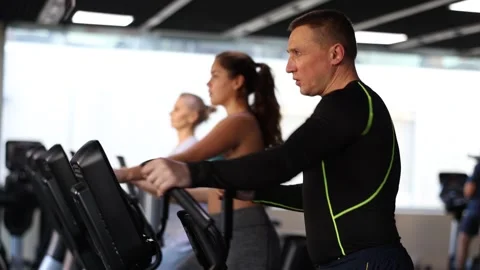 Focused athletic man warming up on elliptical machine before strength training Stock Footage 253761223