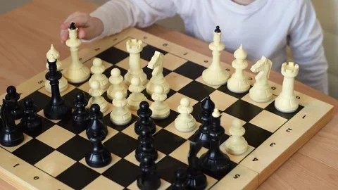 Focused baby boy arranges black chess pieces on the board at home. Stock Footage 150480787