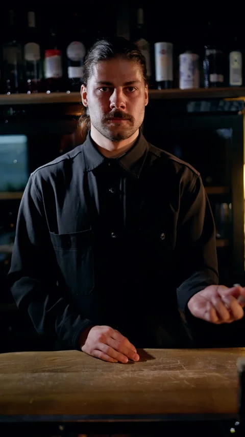 Focused bartender in a dimly lit bar stirring a cocktail behind the counter Stock Footage 318643003