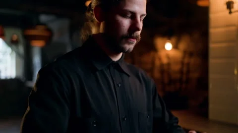 Focused bartender in a dimly lit bar carefully preparing a craft cocktail with Stock Footage 318656215