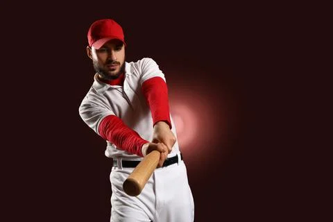 Focused baseball player in red cap and white uniform swinging bat, sports com Stock Photos