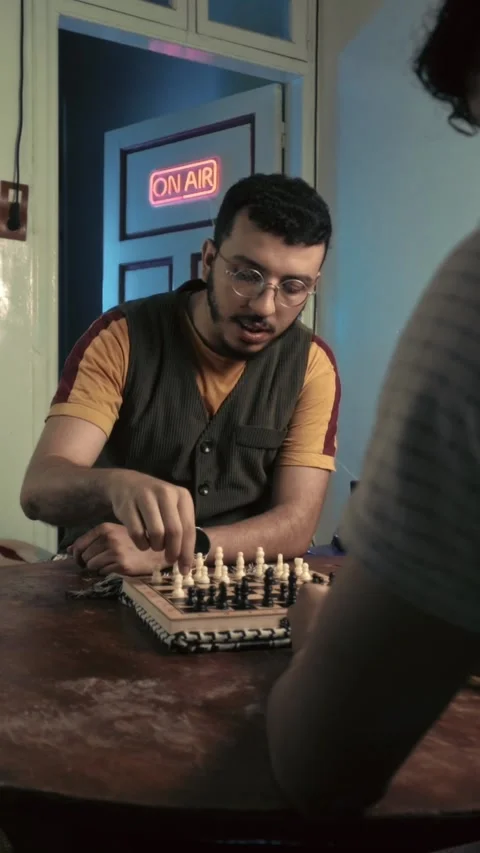 Focused Bearded Man with Glasses Playing Chess and Speaking in Neon Lit Studio Stock Footage 321680043