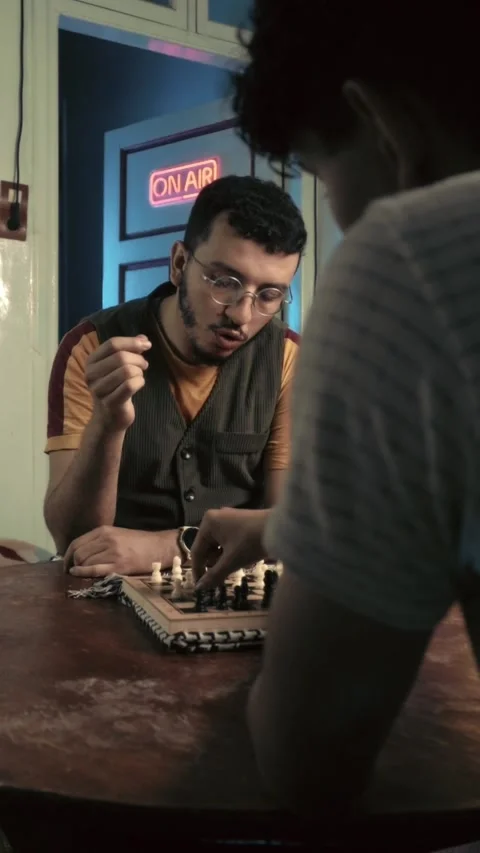 Focused Bearded Man with Glasses Playing Chess and Speaking in Neon Lit Studio Stock Footage 321680048