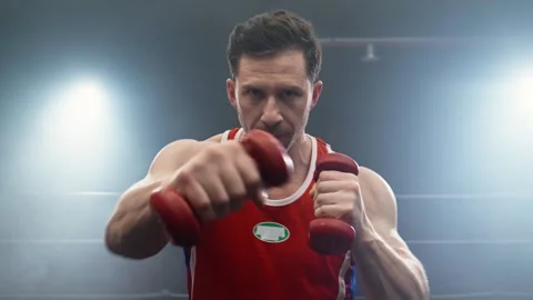 Focused boxer fighter training punches with dumbbells in hands looking at camera Video stock 273207481