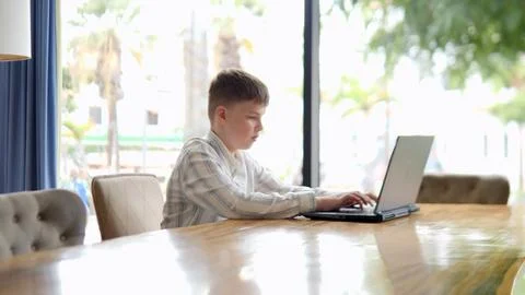 A Focused Boy is Hard at Work Using His Laptop in a Modern and Stylish Work.. Stock Photos