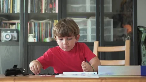 Focused boy sitting at table and assembling parts of game Stock Footage 277224919