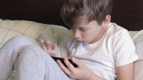 A focused boy taps on the phone screen Stock Footage 159172225