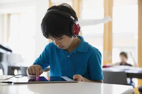 Focused boy using digital tablet with headphones counter Stock Photos