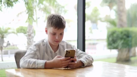 Focused Boy Using Smartphone in Modern Cafe Setting Video stock 317006133