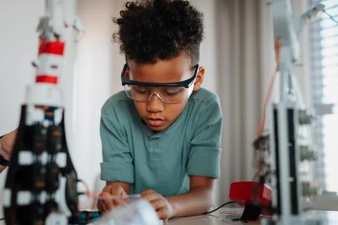 Focused boy working on small robot toy at home. 스톡 사진