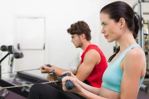 Focused brunette working out on the rowing machine Stock Photos