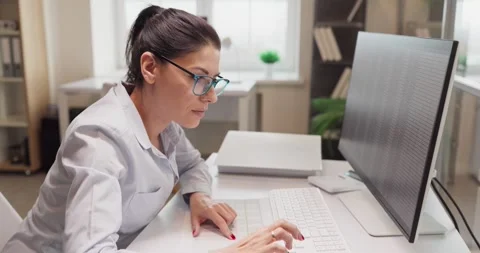 Focused business analyst typing on computer keyboard at monitor in light office Stock Footage 327573140