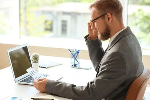 Focused businessman analyzing financial data and business reports on laptop i Stock Photos