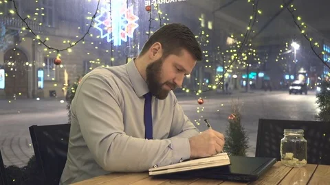 Focused businessman make notes, in cafe, at evening, christmas time Vidéo 72999495