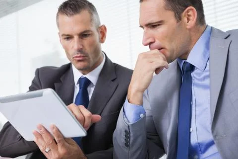 Focused businessmen analyzing documents on their tablet Stock Photos