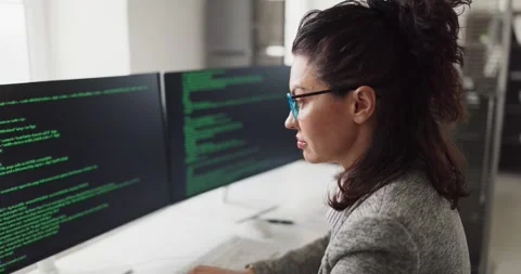 Focused businesswoman developer coding at dual monitors in modern office 動画素材 333161658