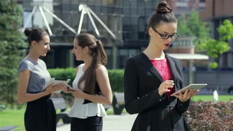 Focused businesswoman using a tablet while her partners engage nearby Stock Footage 311189643
