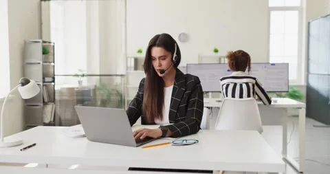 Focused call center operator with headset offering customer support in office Stock Footage 341056477