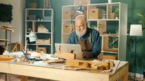 A Focused Carpenter Develops Layouts from Wood Models 3D Sketches Using a Laptop 写真素材