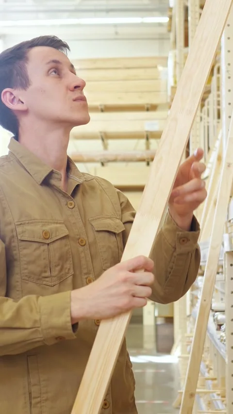 Focused carpenter selecting and inspecting quality wooden plank at hardware Vídeos de archivo 342913558