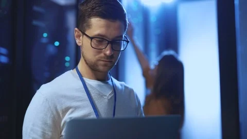 Focused caucasian IT engineer with notebook inspecting work of operative server Stock Footage