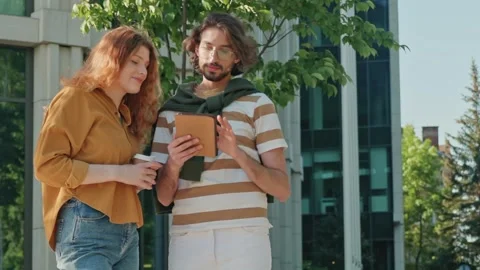 Focused Caucasian man showing something on tablet to curious red-haired woman Stock Footage 307498294