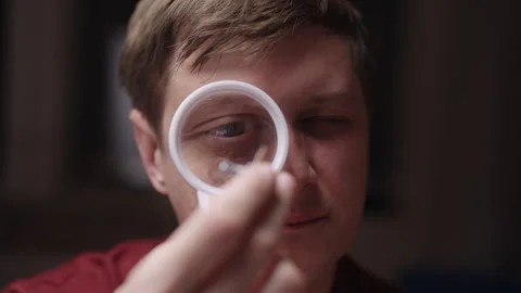 Focused caucasian man using magnifying glass to inspect small electronic Stock Footage 348089465