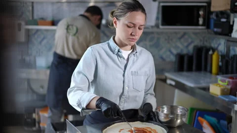 A focused chef is meticulously working in a modern kitchen as he prepares Stock Footage 296634261