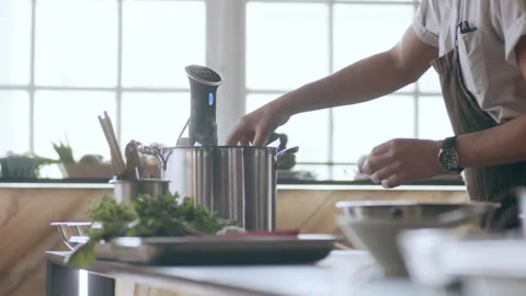 Focused chef placing vacum packed meat into a pot in interior kitchen with soft Stock Footage 199458096