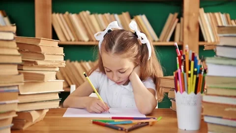A focused child is engaged in the library. Blond white girl with ponytails 8-10 Stock Footage 195011535