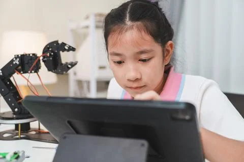 Focused child learning to code on a tablet. Digital literacy and robotics. Stock Photos