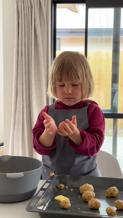 A focused child makes dough balls in the kitchen for cookies. Vertical video Stock Footage 274103763